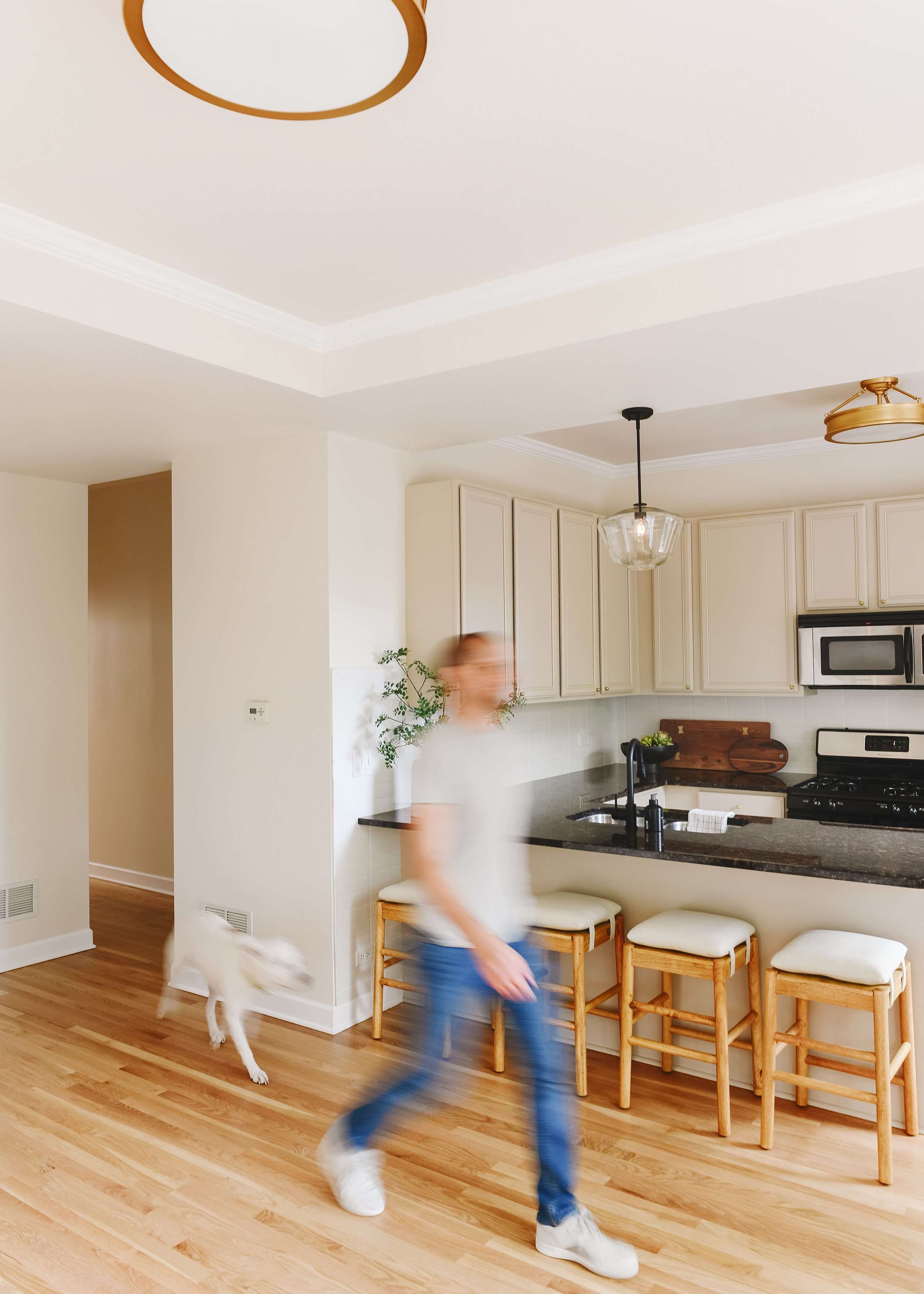Scott and Catfish walk through the refreshed condo space with fresh paint on the walls and cabinets, refinished oak floors and new lighting. | via Yellow Brick Home