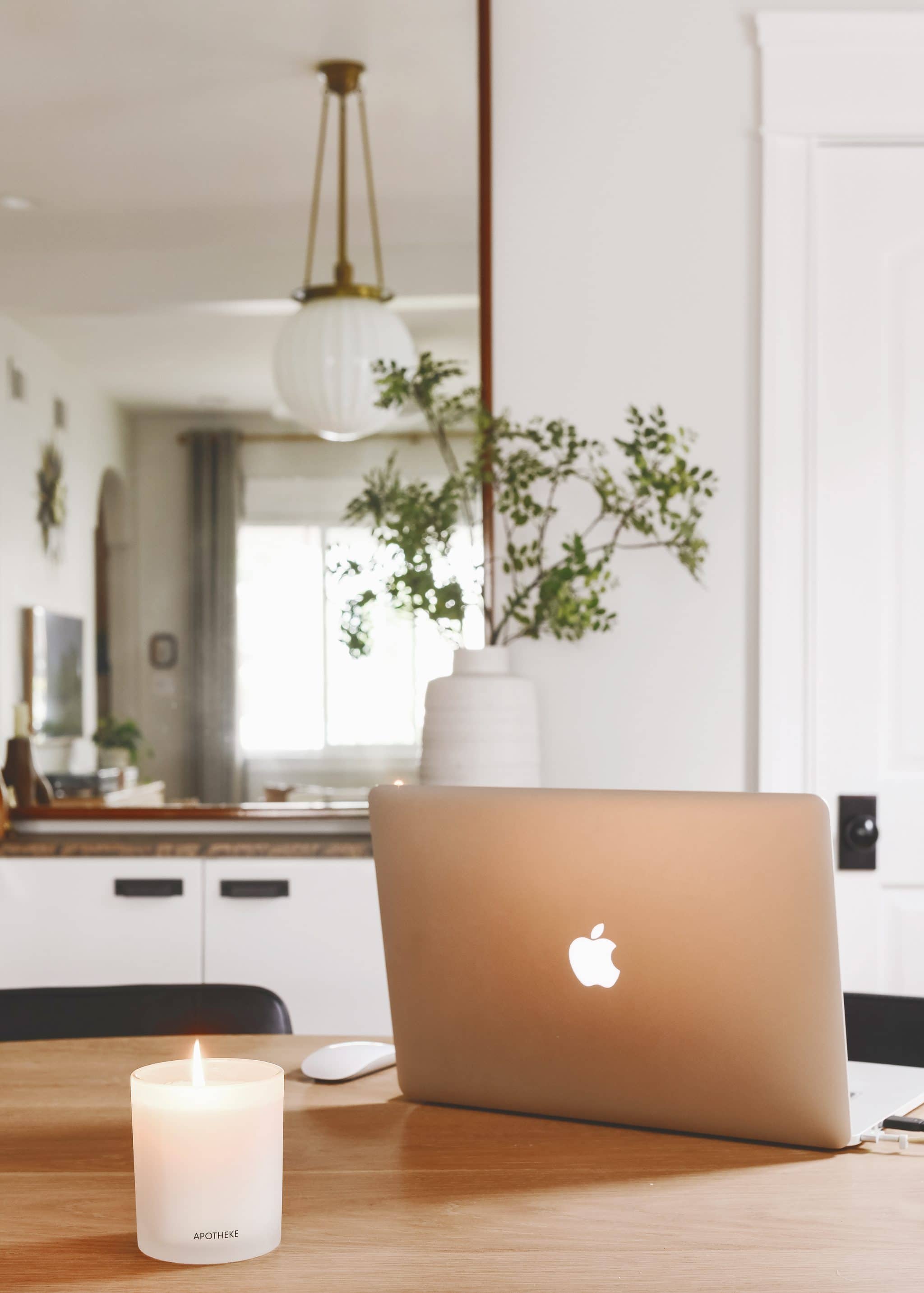 Laptop with a candle burning nearby, portraying a work from home day | the scents that fill our home, via Yellow Brick Home