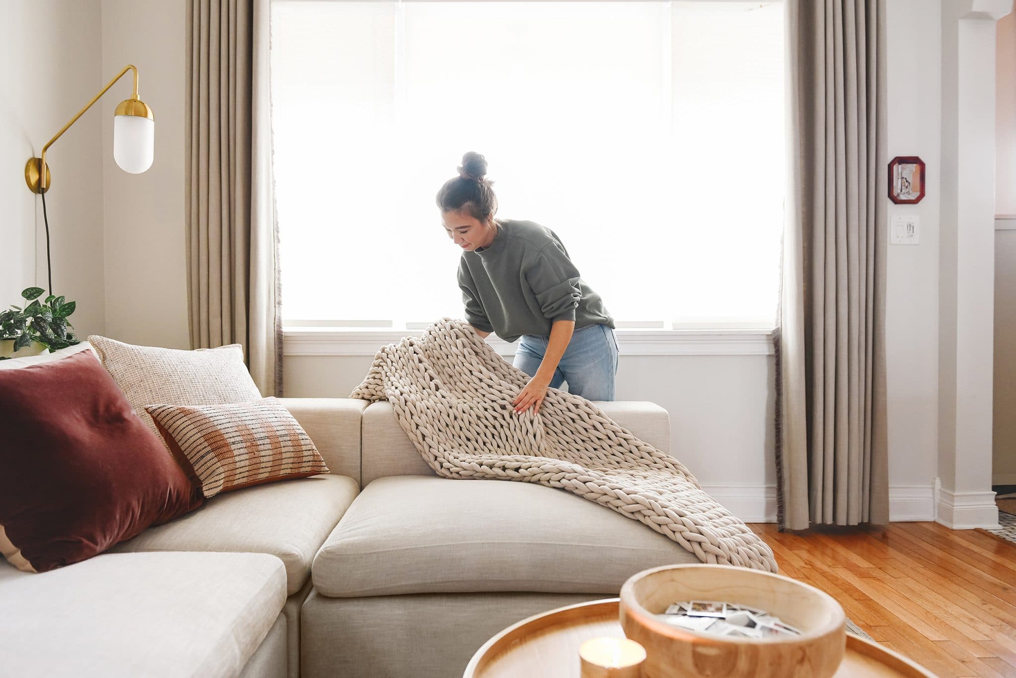 Styling a weighted blanket on the sofa | I'm sharing my simple, inviting formula for styling pillows on an L-shaped or U-shaped sofa, via Yellow Brick Home