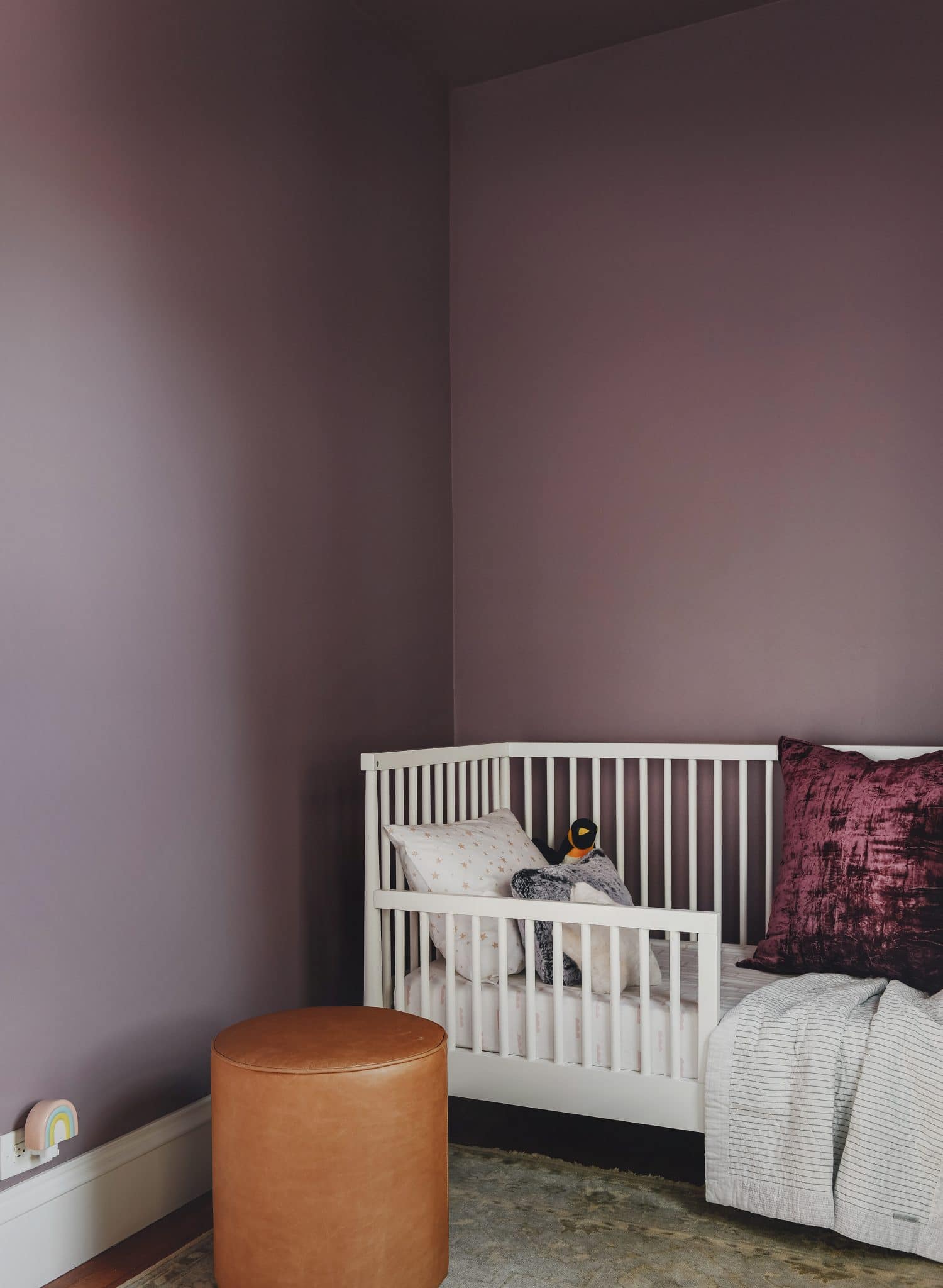 Lucy's bed with purple walls and a leathr ottoman | color is Valspar Mellow Mauve 1004-7C | via Yellow Brick Home