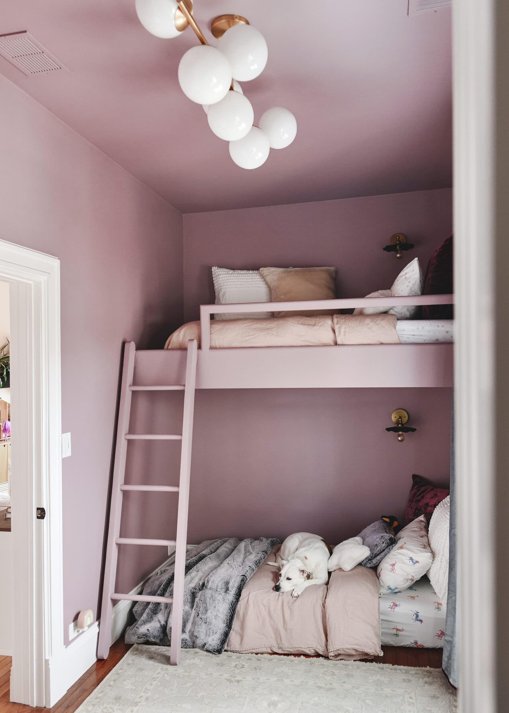 A pulled back view of a loft bed with purple walls | Lighting round up for kids and adults! | via Yellow Brick Home