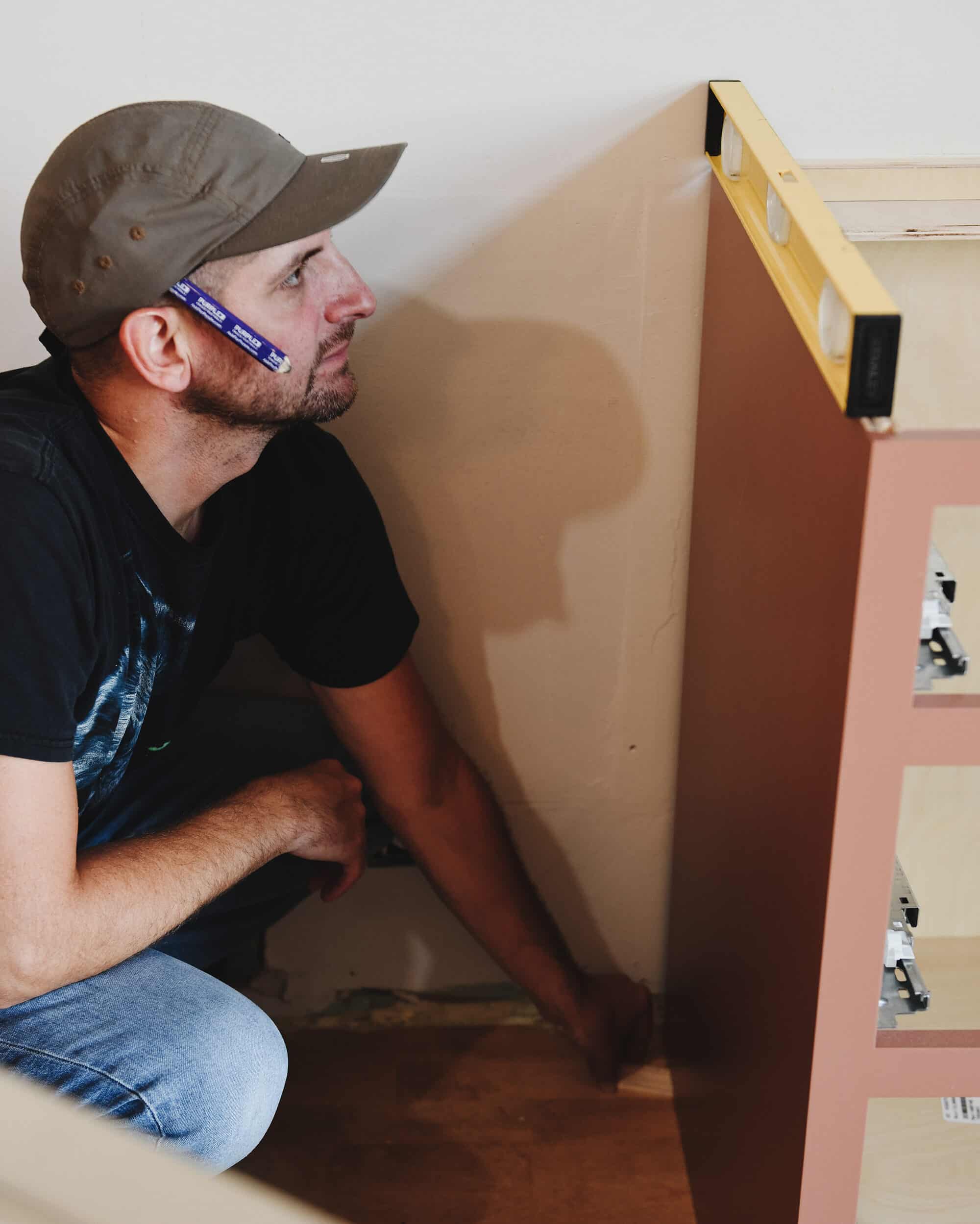 Scott checks a cabinet for level while adjusting a shim // via Yellow Brick Home