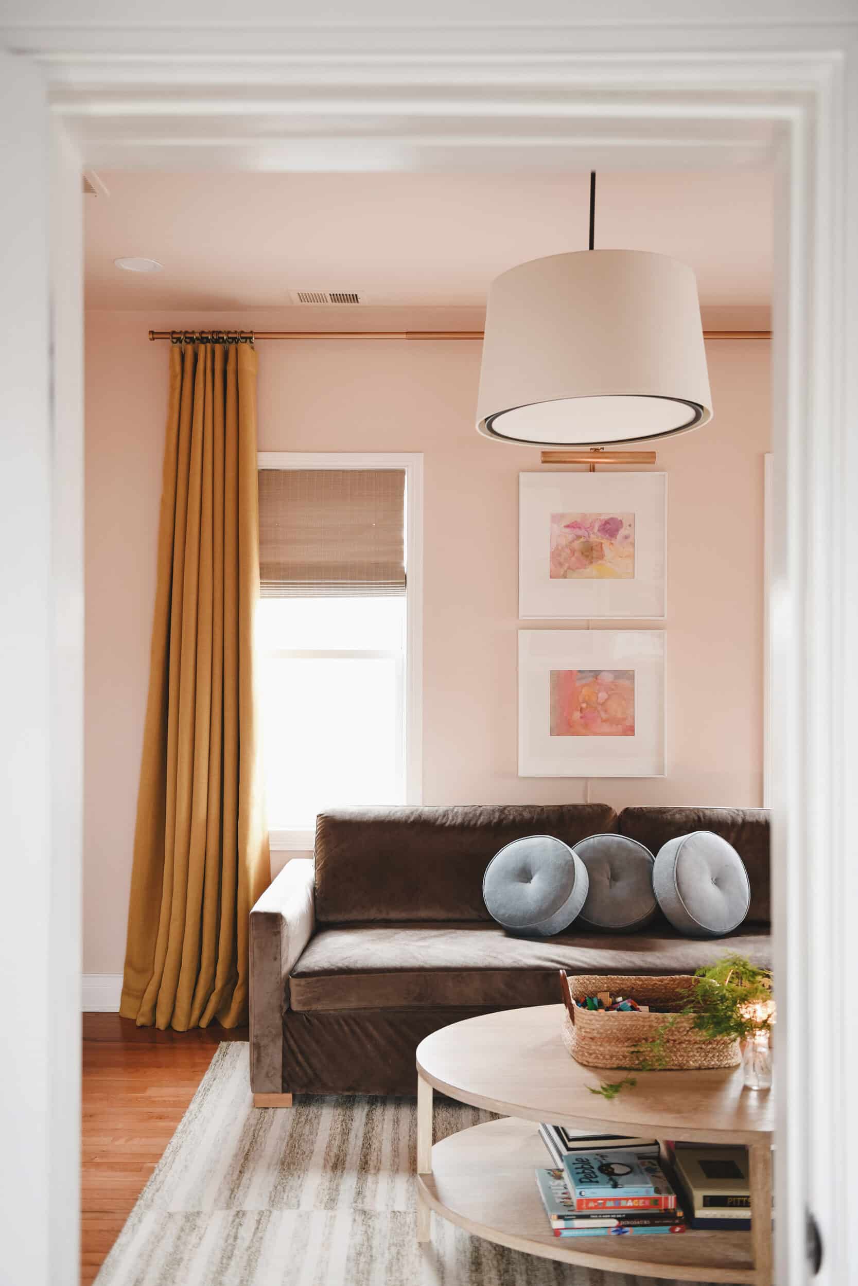 Family room with peach walls, gold curtains and velvet sofa | via Yellow Brick Home