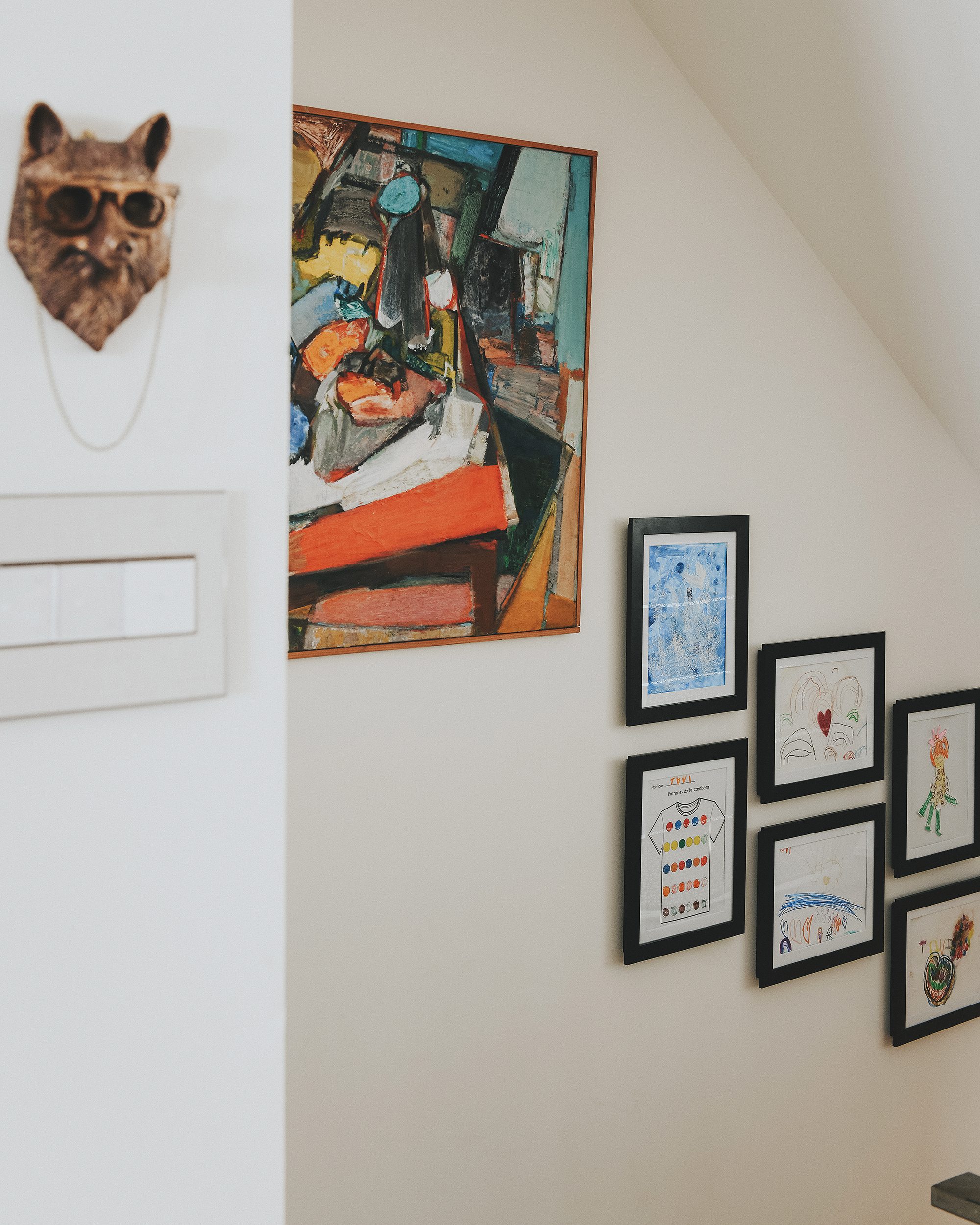 Hallway of frames with vintage painting and kids' art  | via Yellow Brick Home