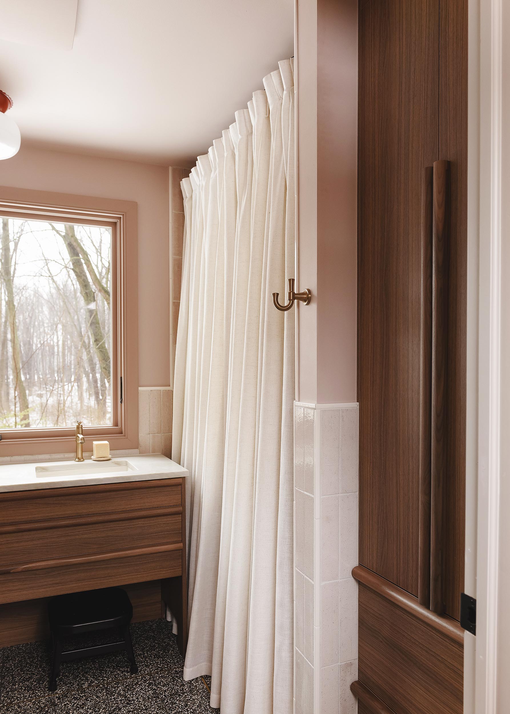 Floor to ceiling shower curtain in a pink bathroom with walnut and brass accents | via Yellow Brick Home
