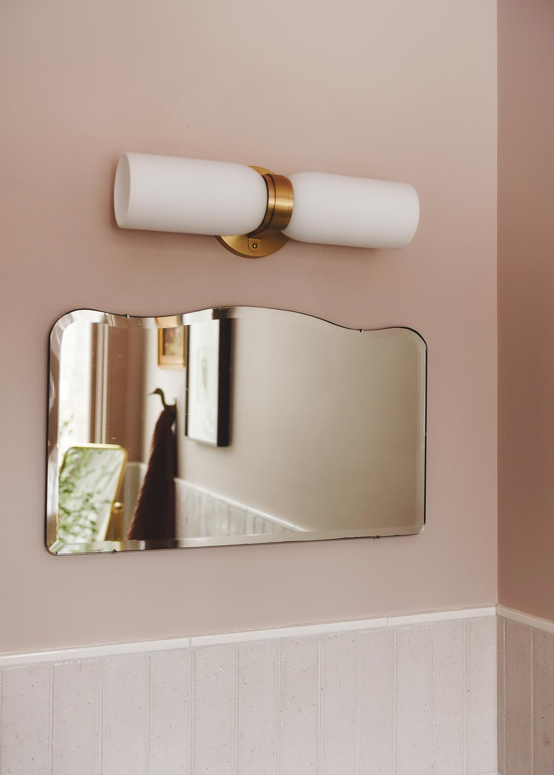 detail of vintage mirror and brass sconce in pink bathroom | via Yellow Brick Home
