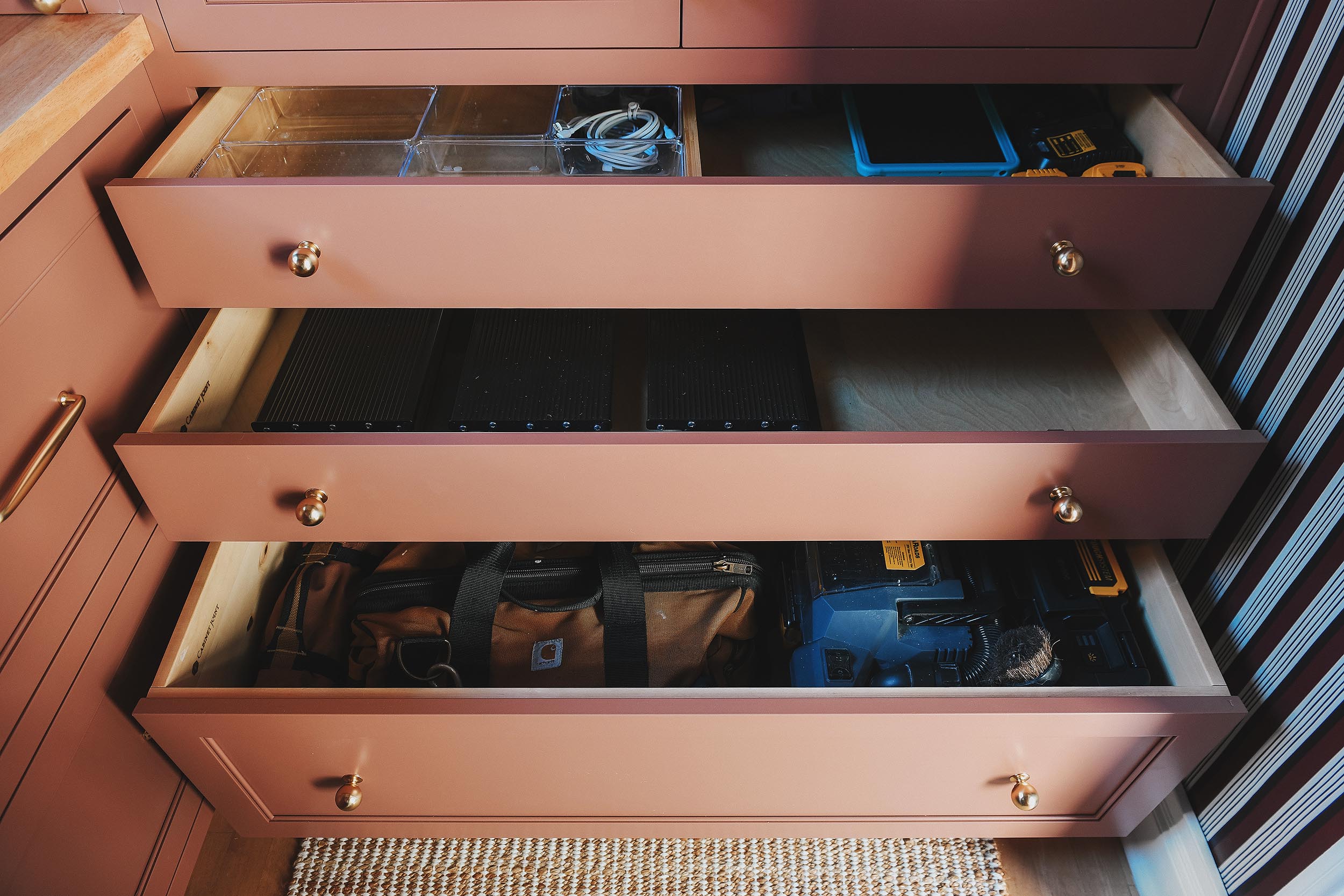 The pantry's largest cabinet features three wide drawers with a charging station, ladder storage and tool storage The pantry's largest cabinets is full of bins to keep everything organized // via Yellow Brick Home